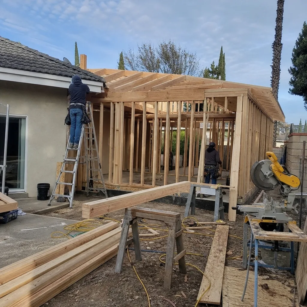 Contractors building a wooden home addition frame on a residential property.