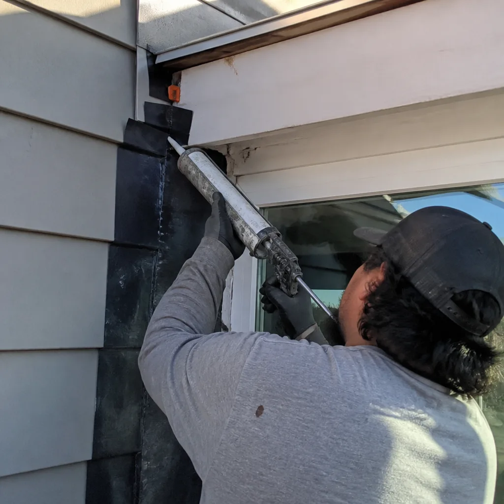 Contractor applying sealant to exterior flashing on a home addition project